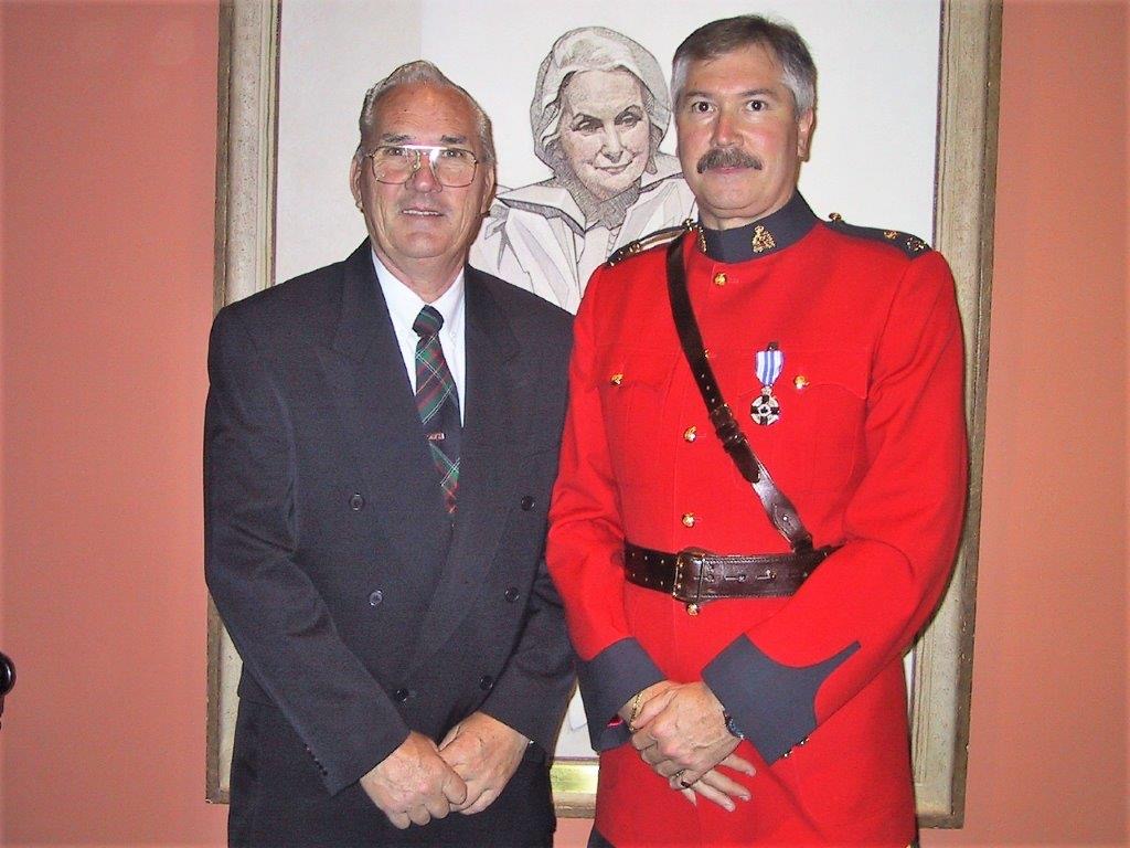 Gordon Black in RCMP red serge wearing his Meritorious Service Medal, standing beside his father Archie.